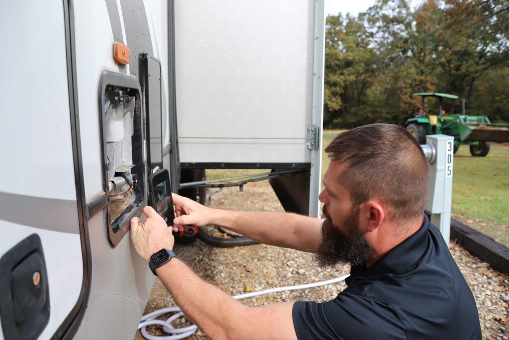 An RV inspector carefully examines the exterior of a recreational vehicle, focusing on the roof and side panels to check for signs of damage, wear, or leaks, ensuring the vehicle is safe and road-ready.